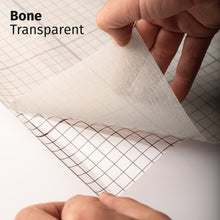 Cargar imagen en el visor de la galería, Bone Transparent adhesive textile film with grid-lined clear backing, shown being peeled back to demonstrate its semi-transparent finish and easy application.